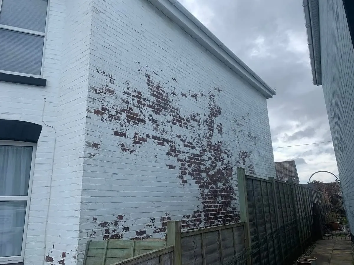 Peeling paint on a brick wall before redecoration in Wadebridge